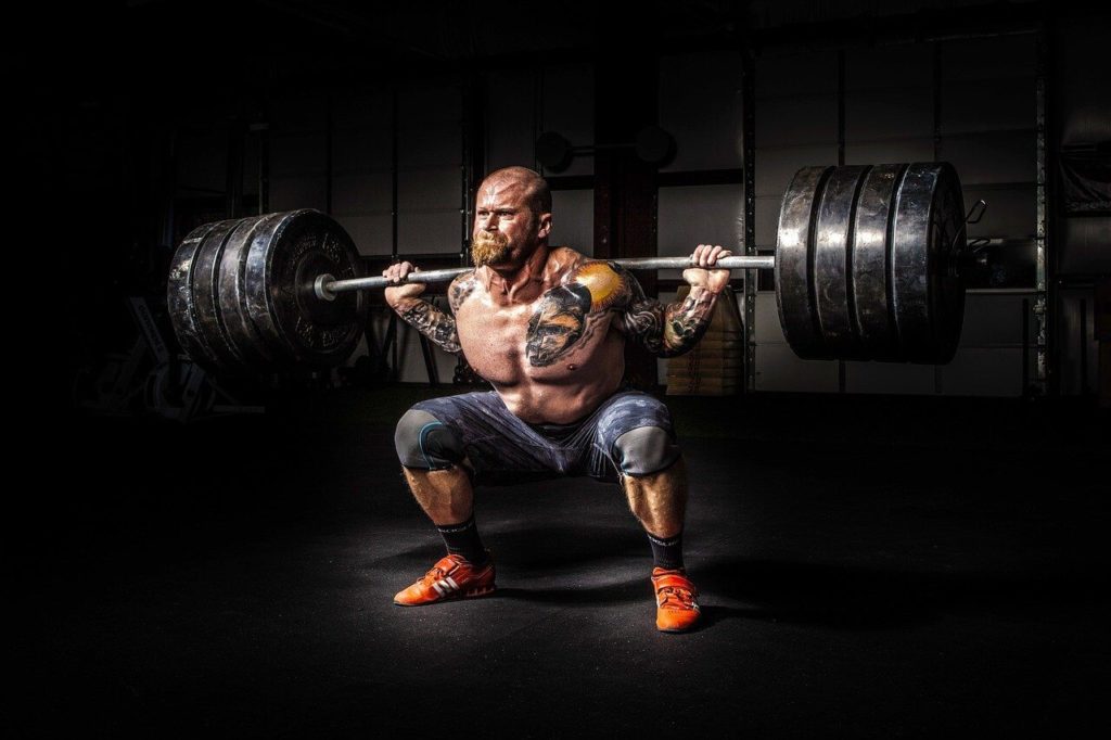 Shirtless man lifting 405 pounds with weightlifting shoes on.